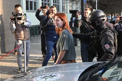 Policisté obviněnou přivádějí k vazebnímu jednání. 