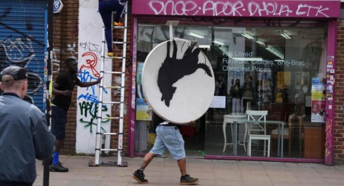 Jeden ze zlodějů si odnáší satelit s dílem od Banksyho.