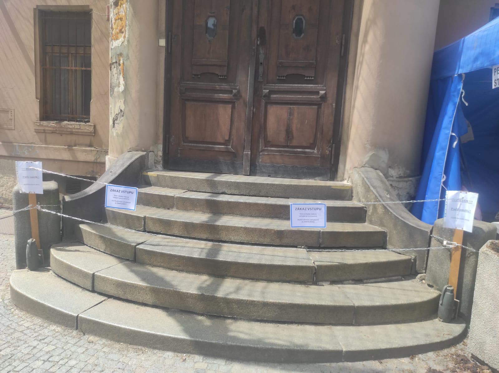 Cedule zakazující vstup na schody vedle petičního stánku.